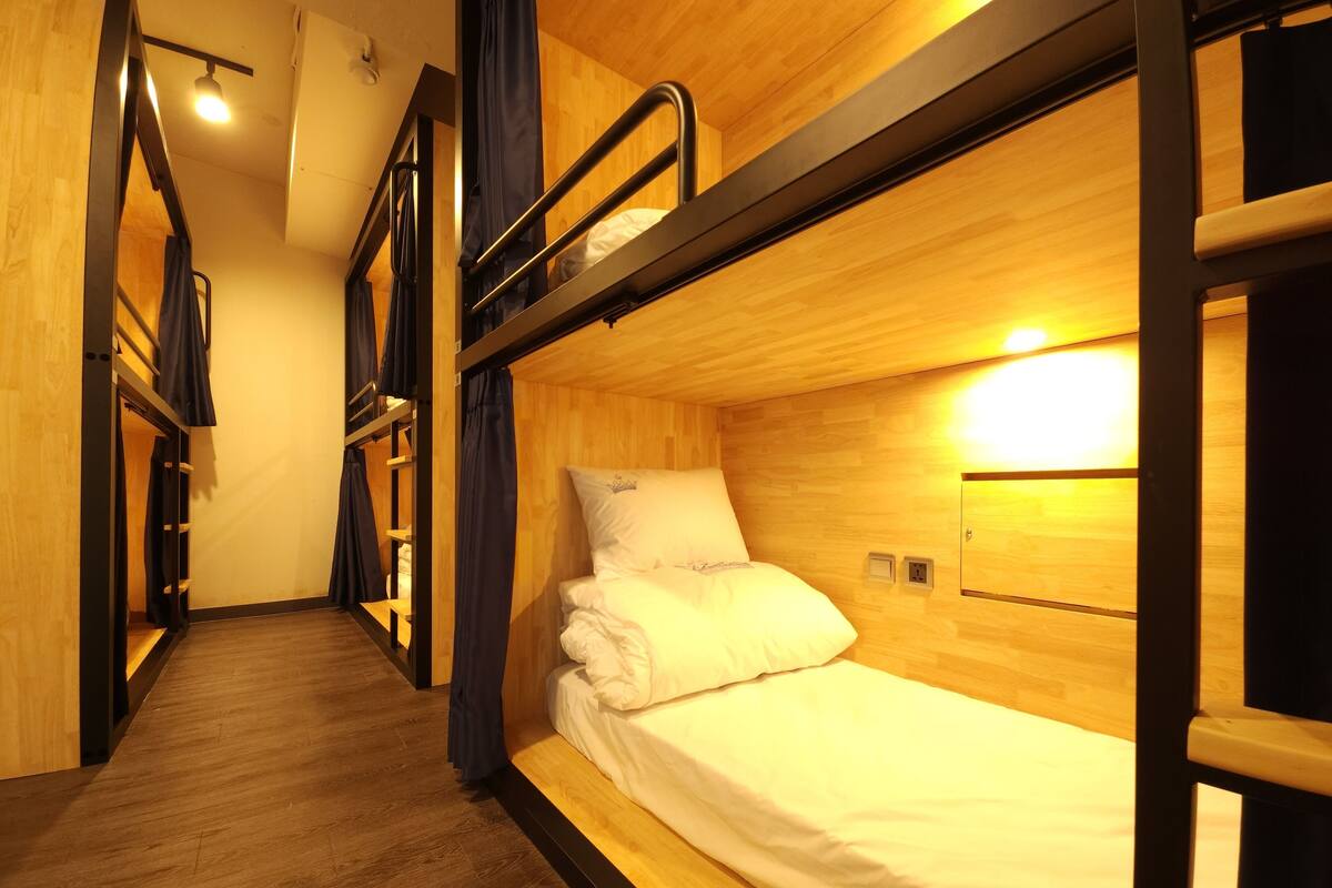 Dormitorio con literas, paredes y suelo de madera.