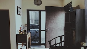 A room with a bicycle, a desk with items, a chair, and a door leading to a balcony. - Yujing Mountain Water Residence I (Tainan)