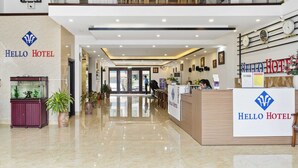 A modern hotel lobby with a reception desk, a fish tank, and potted plants. - Nara Hotel (Kinh Bac)