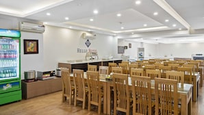 A hotel dining area with multiple tables and chairs, a Sprite refrigerator, and a kitchen area with a microwave and toaster. - Nara Hotel (Kinh Bac)