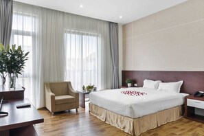 A hotel room with a large bed, a chair, a desk, and a potted plant. - Nara Hotel (Kinh Bac)