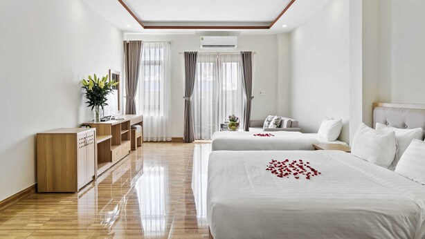 A hotel room with two beds, a wooden cabinet, a desk, and a large window with curtains. - Nara Hotel (Kinh Bac)