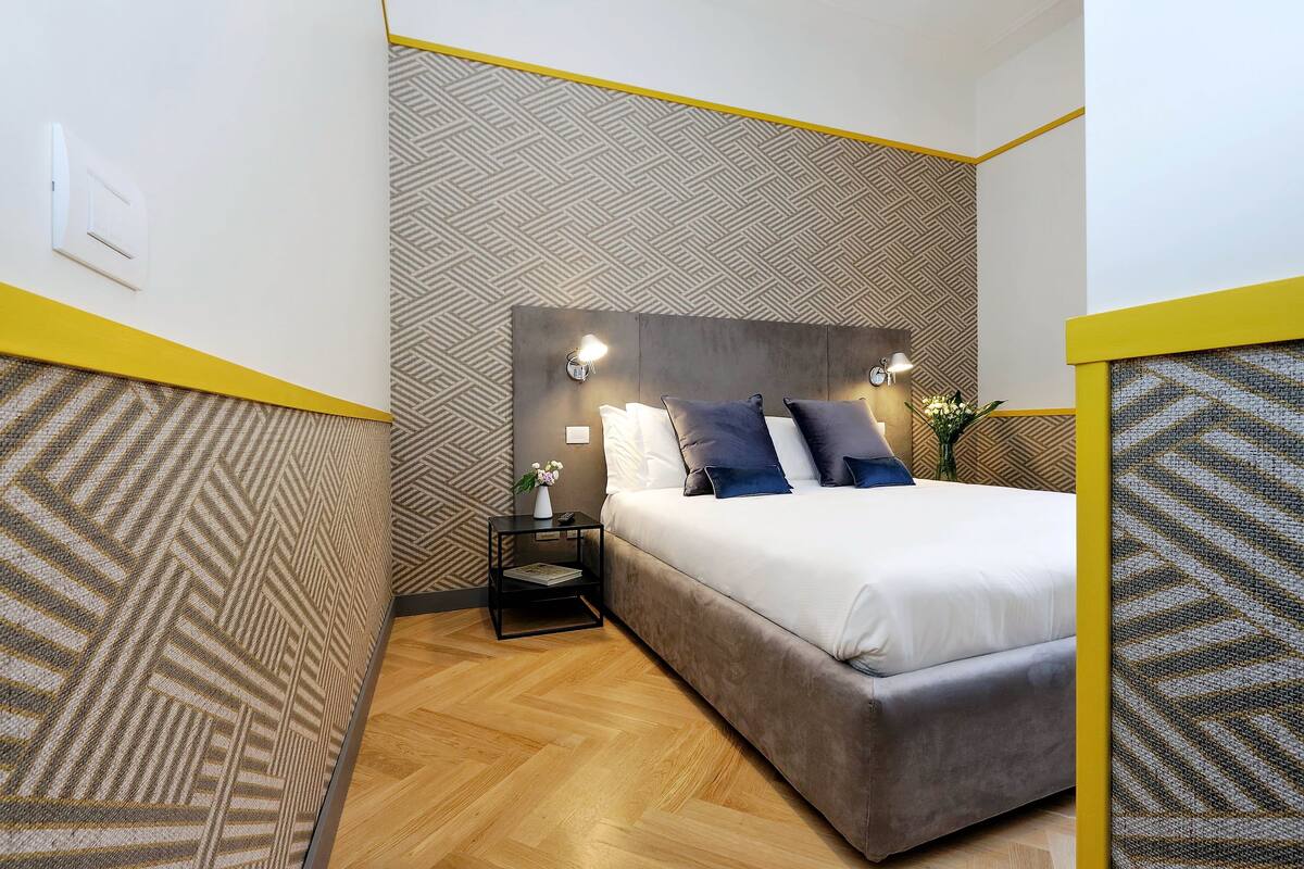 A bedroom with a bed, bedside tables, and a patterned wall.