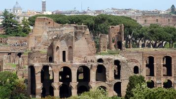 Ruinas antiguas con múltiples arcos y un paisaje urbano al fondo.