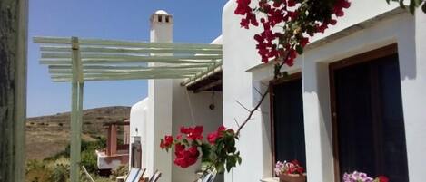 A white building with a balcony, a hammock, and potted plants.