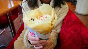 Uma pessoa segurando um cone com sobremesa, possivelmente sorvete, em copo de papel.