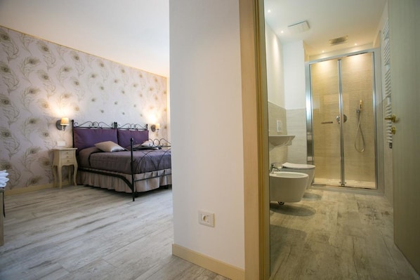 Une chambre à coucher comprenant un lit, des tables de chevet et une salle de bain avec douche, toilettes et baignoire.