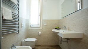 A bathroom with a toilet, bidet, sink, and towel rack. - Dolce Laguna (Mestre)