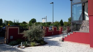A red building with a glass entrance, a paved walkway, and a street lamp. - Dolce Laguna (Mestre)