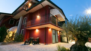 A two-story building with a balcony, outdoor seating, and a well-lit entrance. - Dolce Laguna (Mestre)