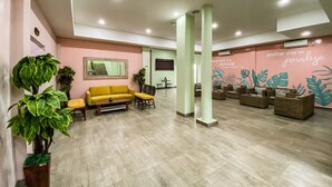 A spacious lobby with a yellow sofa, multiple seating areas, and a wall mural. - Hotel Moloka’I Morotai (Morotai Island)