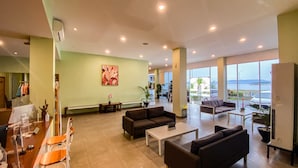 A spacious lobby with a large seating area, a reception desk, and a view of the sea. - Hotel Moloka’I Morotai (Morotai Island)