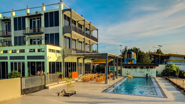 A modern hotel with a rooftop pool area, outdoor seating, and a covered patio. - Hotel Moloka’I Morotai (Morotai Island)