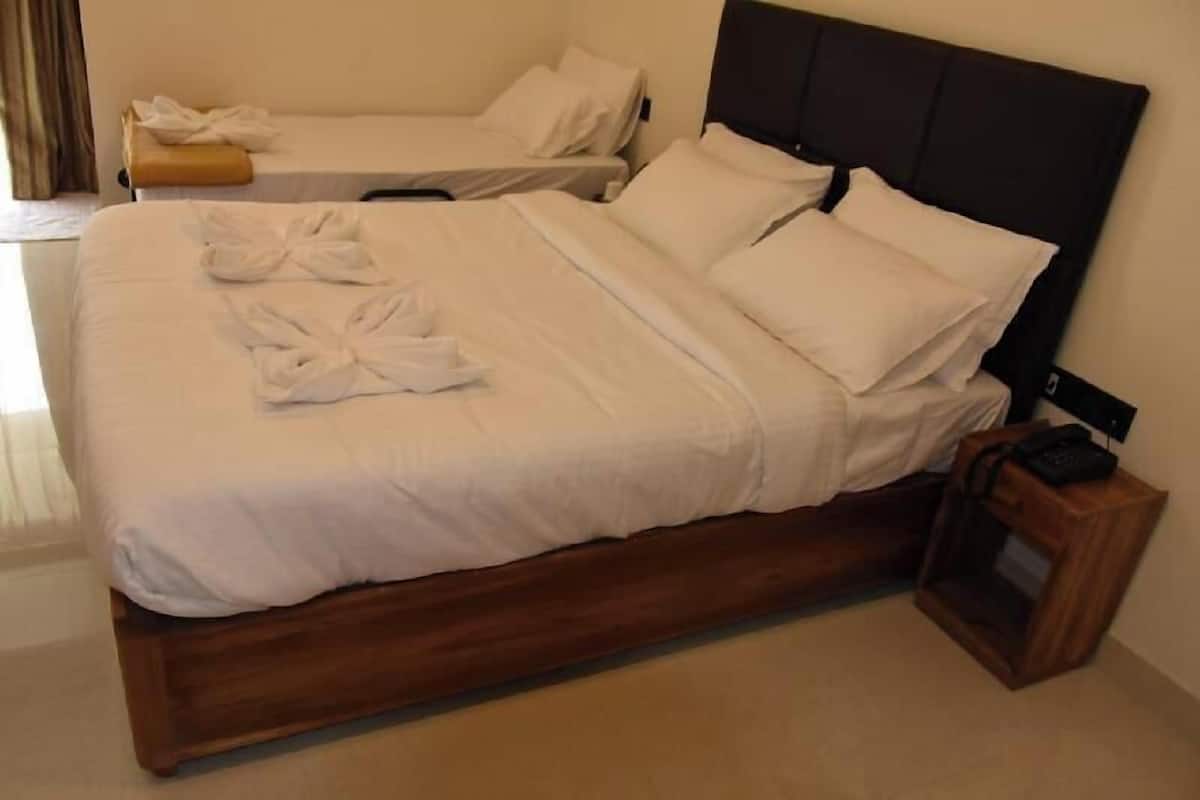 A double bed with white linens, a wooden headboard, and a bedside table with a phone.