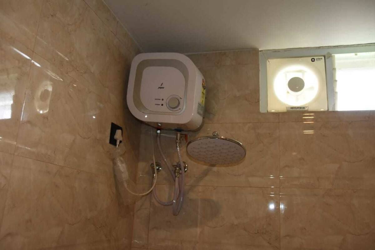 A bathroom with a built-in shower unit, a wall-mounted toilet, and a window with a circular light fixture.