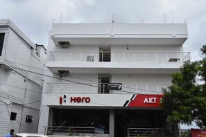 Un edificio de varios pisos con fachada blanca, que muestra un letrero 'Hero' en la planta baja y un letrero 'AKT' en el nivel superior.