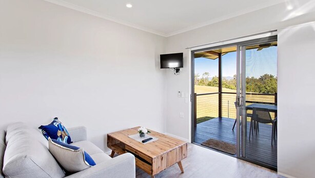 A modern living room with a sofa, a wooden coffee table, and a TV mounted on the wall.