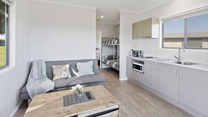A compact, modern apartment with a kitchenette, a sofa, and a dining area.