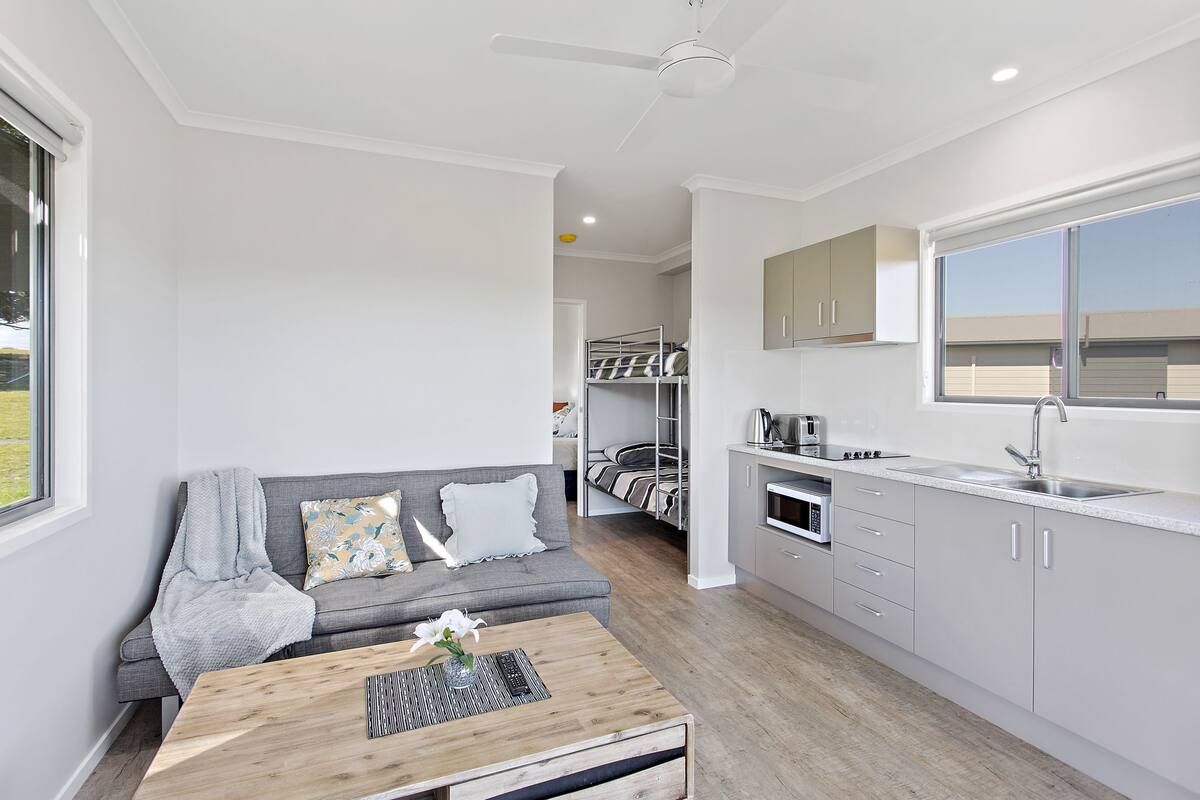 Un apartamento moderno y compacto con kitchenette, un sofá y un comedor.