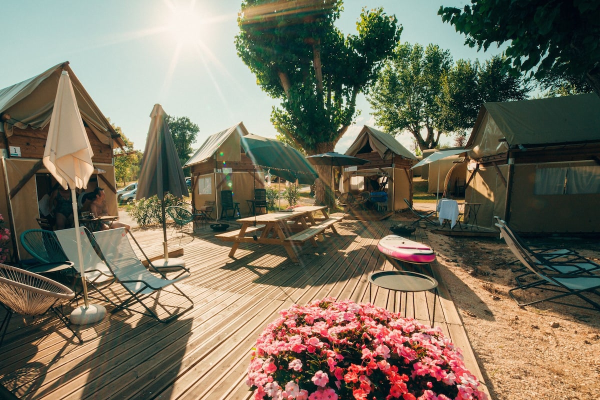 A wooden deck with lounge chairs, a picnic table, and a flower bed.