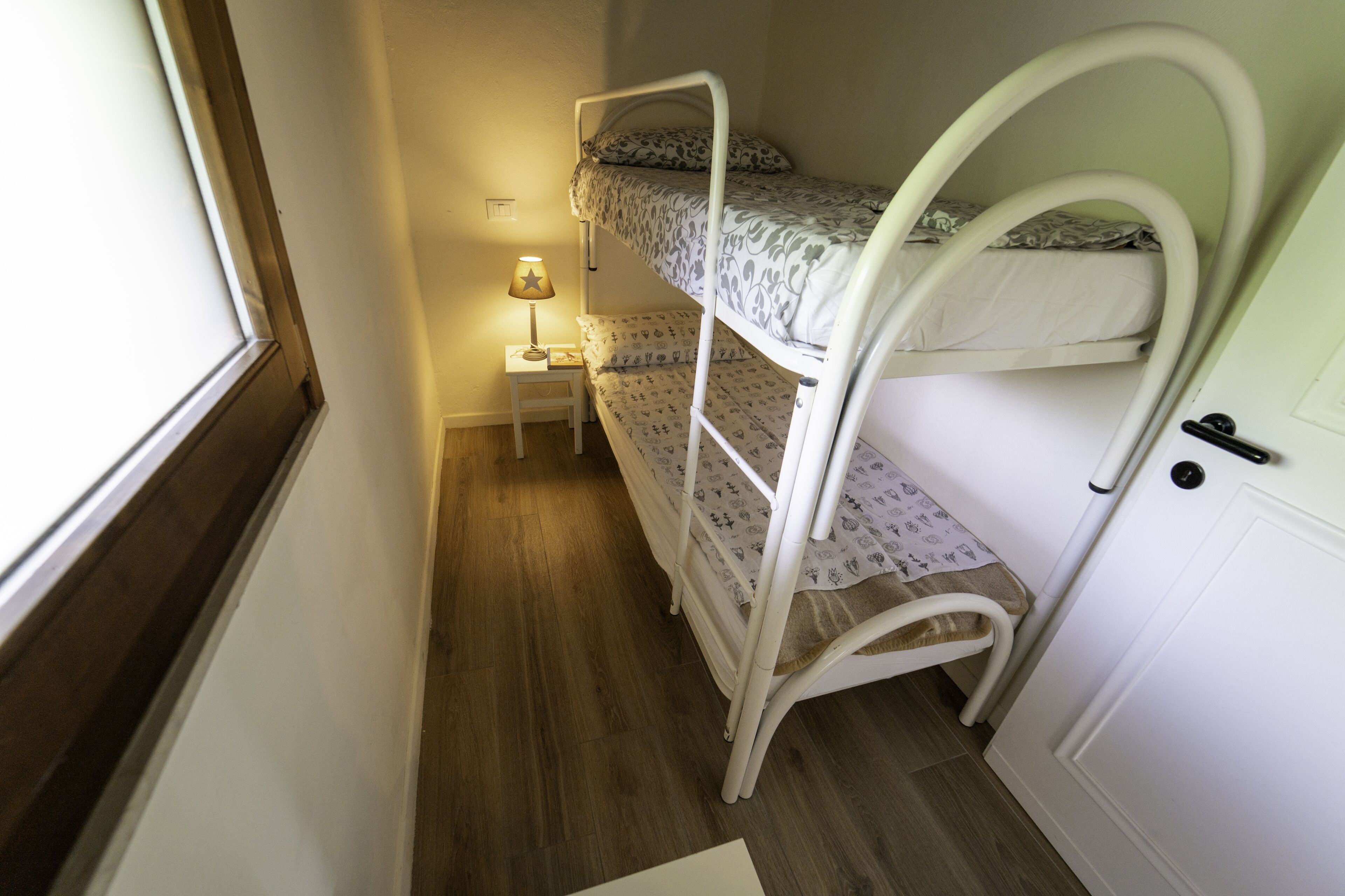 A bunk bed room with a small bedside table and lamp.