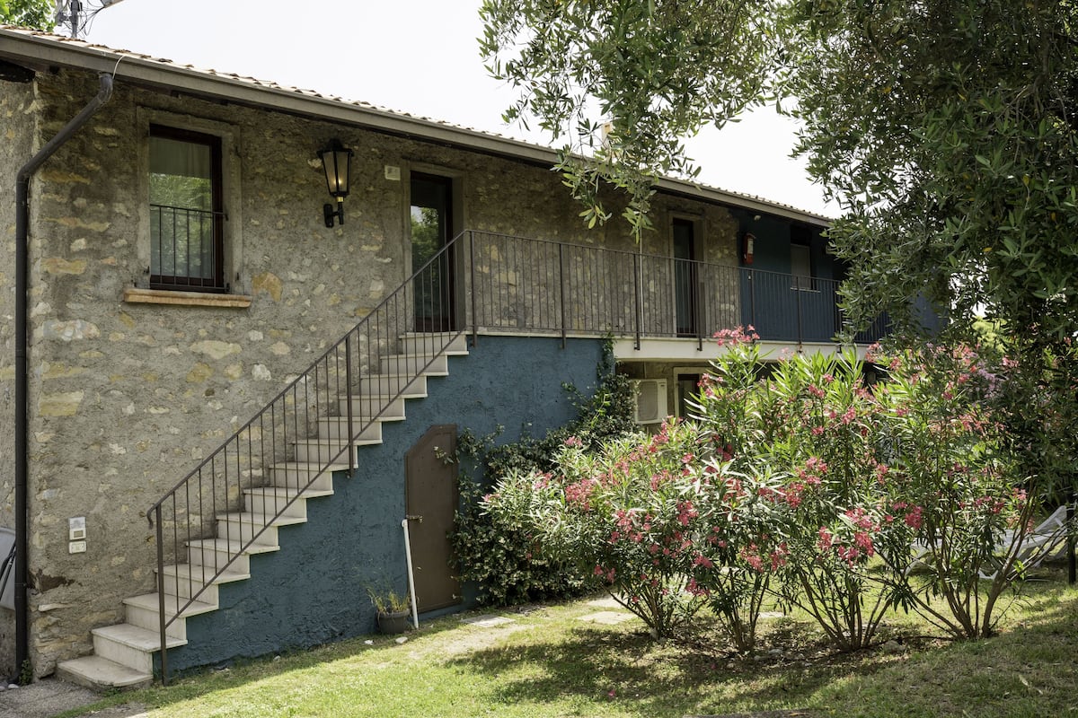 A two-story stone building with a staircase leading to the upper floor.