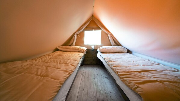 A small, triangular attic room with two single beds and a wooden floor.
