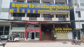 A hotel with a prominent sign in a foreign language, a covered entrance, and a staircase leading to the entrance. - Wei Si Deng Hotel and Restaurant (Phnom Penh)
