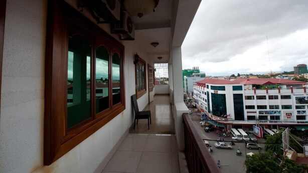 A balcony with a view of a busy street and a building with multiple floors and shops. - Wei Si Deng Hotel and Restaurant (Phnom Penh)