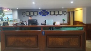 A reception desk with a computer, a clock, and a sign with multiple time zones. - Wei Si Deng Hotel and Restaurant (Phnom Penh)