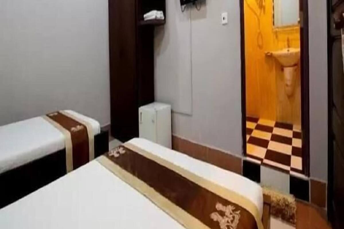 Una habitación con dos camas, un armario, un televisor y un baño visible a través de una puerta abierta.