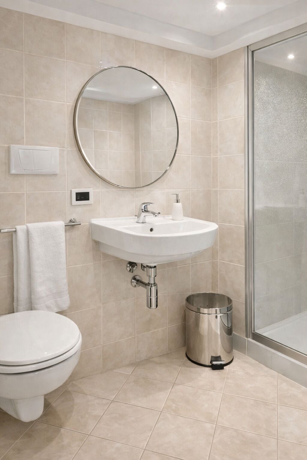 Een badkamer met een witte wastafel, een ronde spiegel, een toilet en een prullenbak.