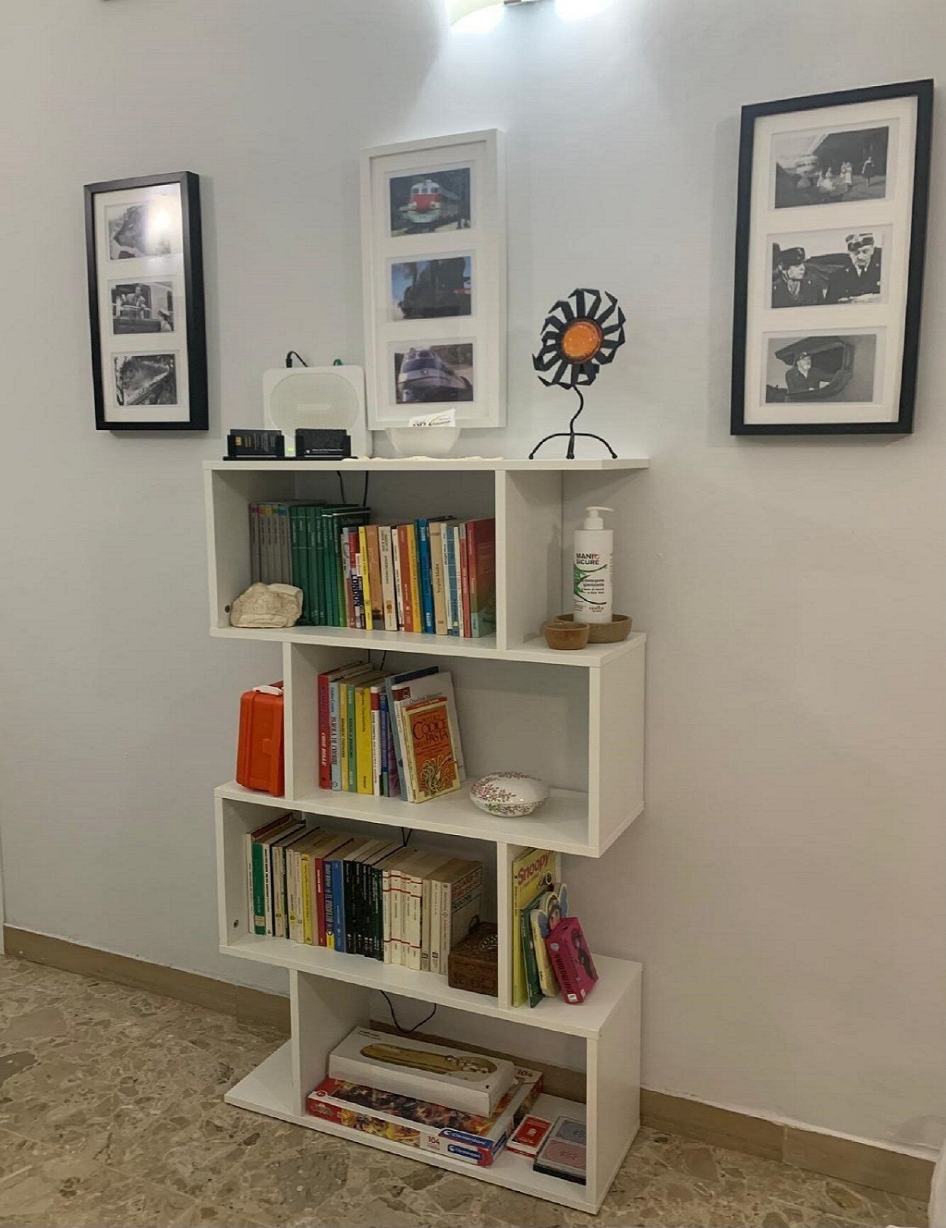 Una libreria bianca con diversi libri e un piccolo oggetto decorativo sopra.