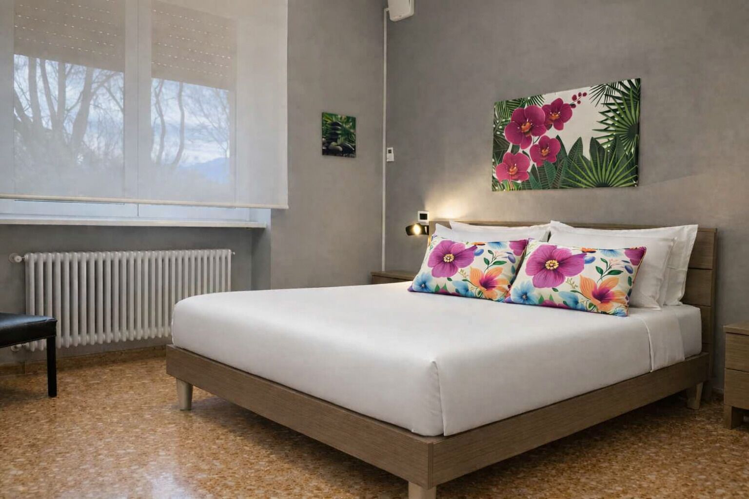 Ein Schlafzimmer mit einem Bett, einem Sessel, einem Heizkörper und einer Wand mit einem Blumenbild.