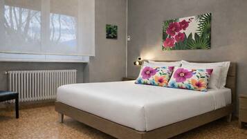 Ein Schlafzimmer mit einem Bett, einem Sessel, einem Heizkörper und einer Wand mit einem Blumenbild.