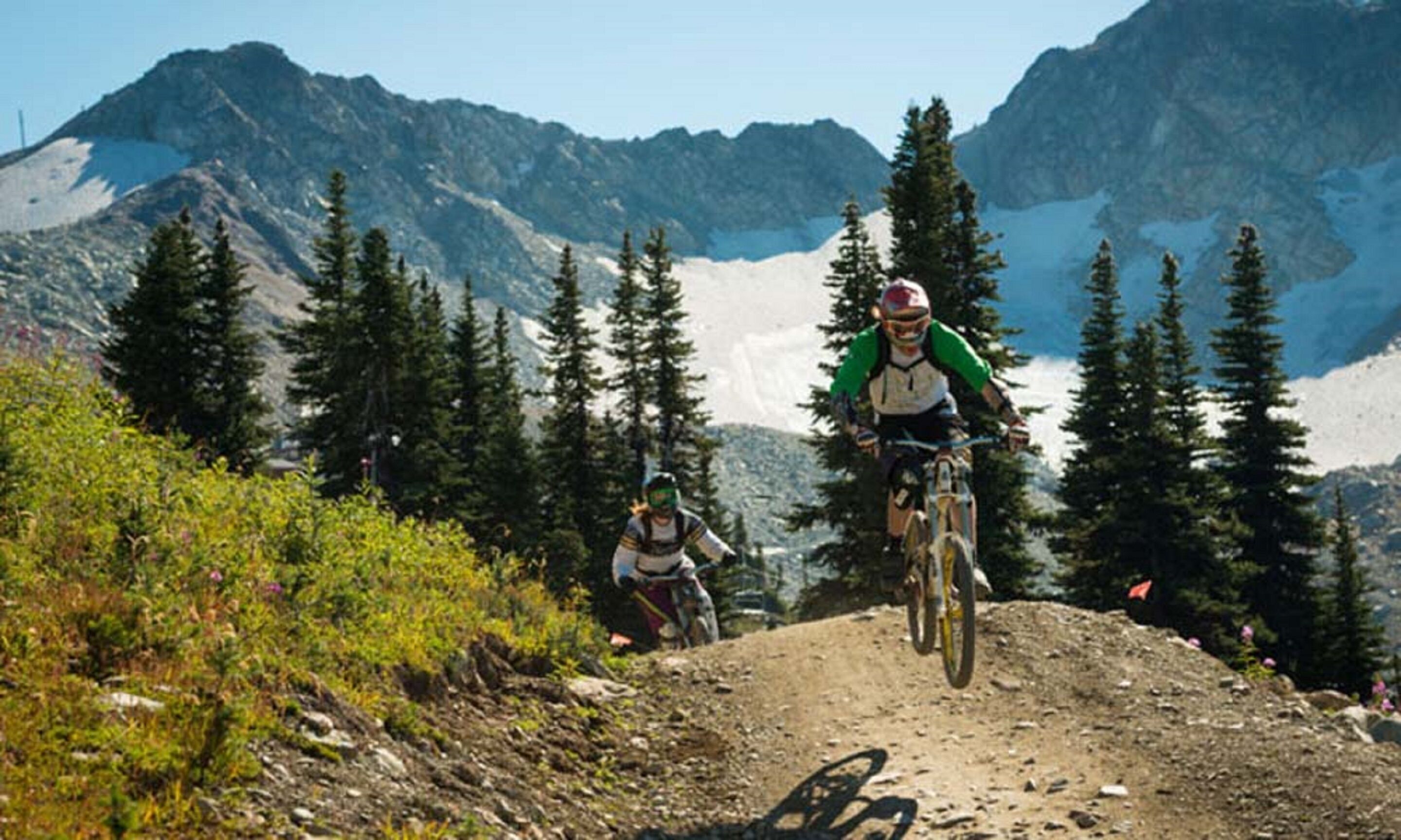A mountain biking trail with a clear view of the surrounding mountains and trees.