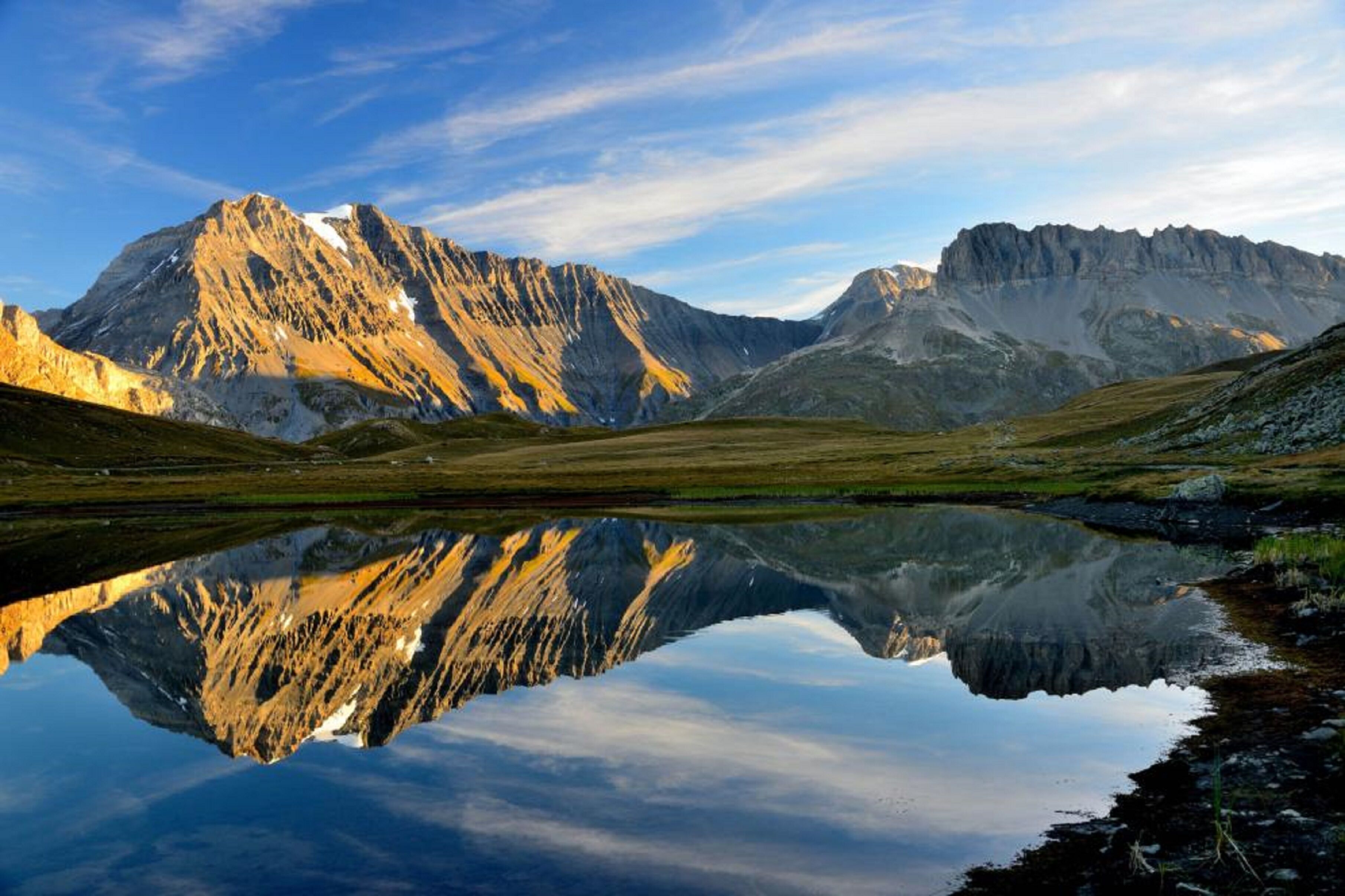 Un paysage de montagne se reflétant clairement dans une étendue d’eau calme.