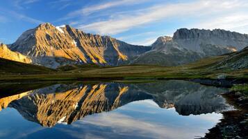 Eine Berglandschaft spiegelt sich klar in stillen Gewässern.
