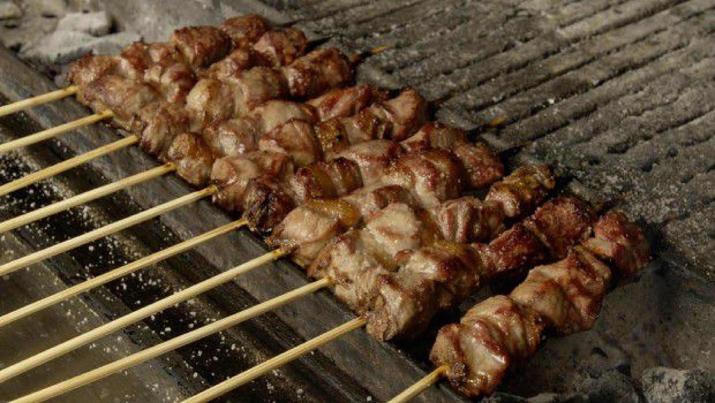 Skewers of meat being grilled on a barbecue.