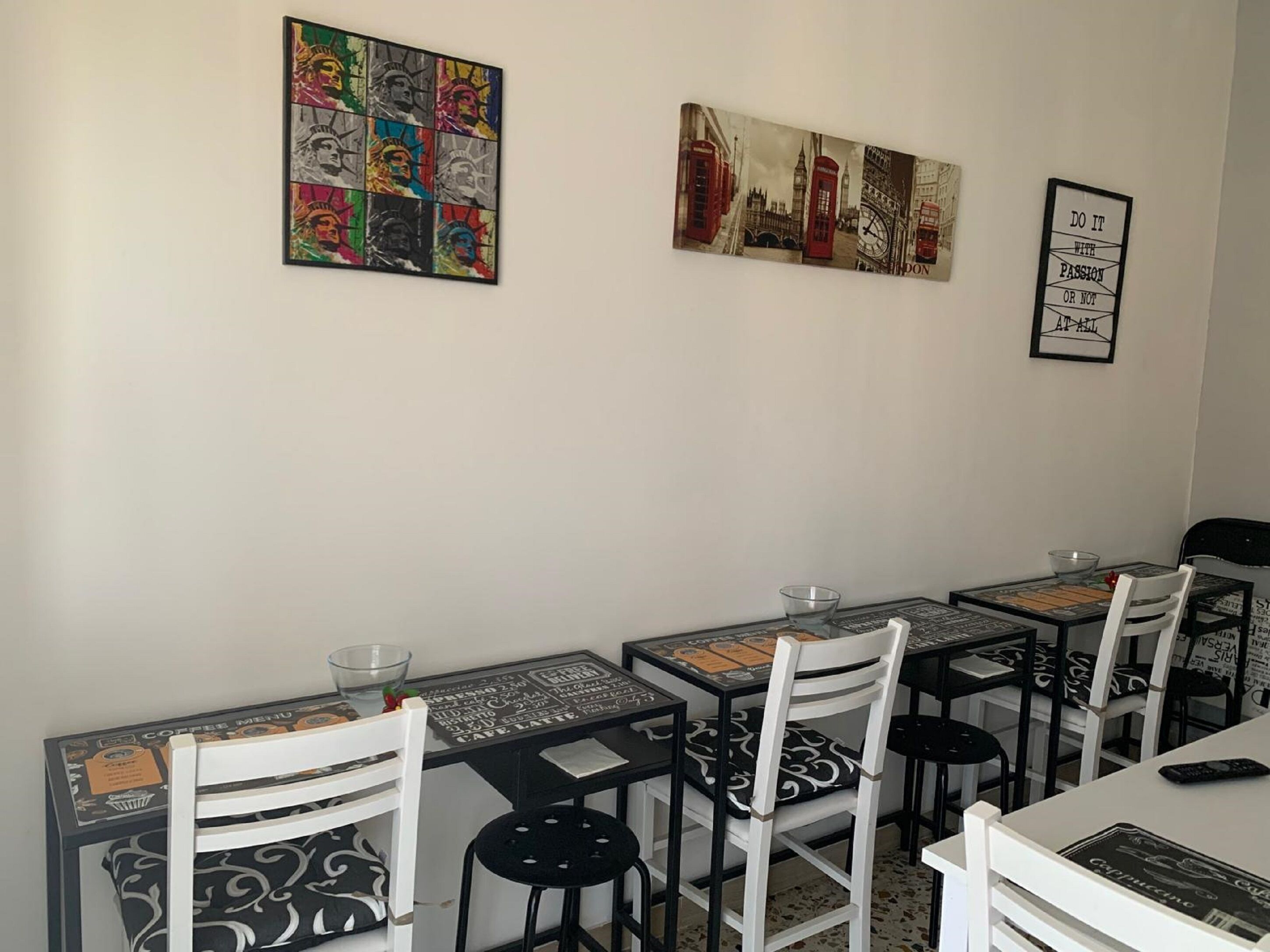 Ein Essbereich mit Tischen, Stühlen, einer Kaffeekarte und Kunstwerken an den Wänden.