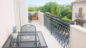 A balcony with a table and chairs, potted plants, and a view of greenery and buildings. - B &B Residence Armonia (Sulmona)