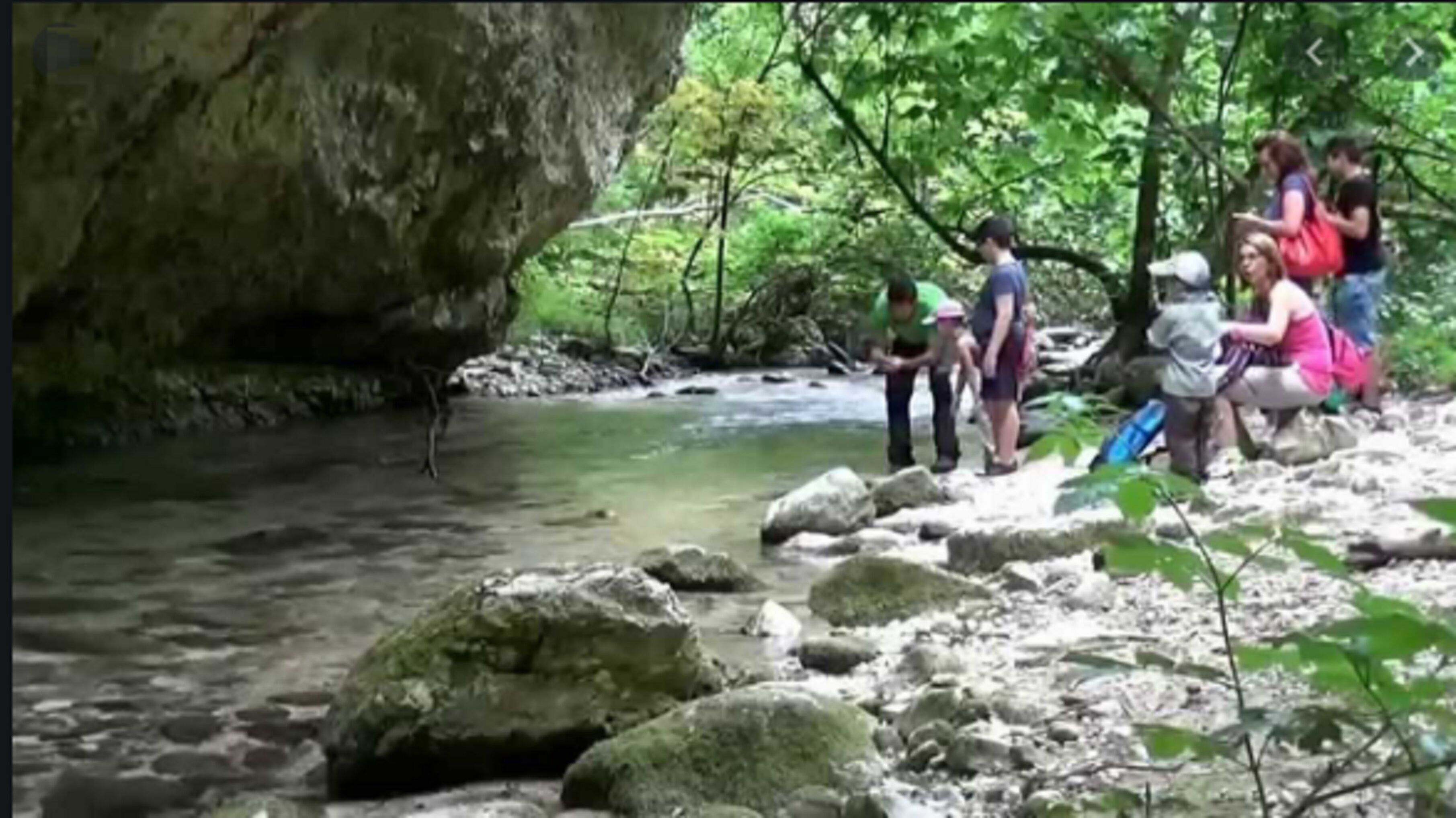 Un paysage naturel avec une rivière, des rochers et des personnes.
