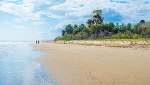 A beach with a tower on a hill, clear skies, and two people walking. - B &B Residence Armonia (Sulmona)
