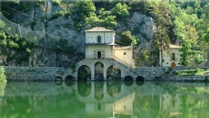 A building with a stone bridge over water, arched passageway, and a reflection in the water. - B &B Residence Armonia (Sulmona)
