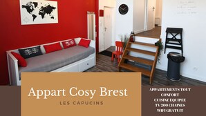 A modern living room with a red accent wall, a world map, and a cozy sofa. - Appart Cosy Brest Les Capucins (Brest)