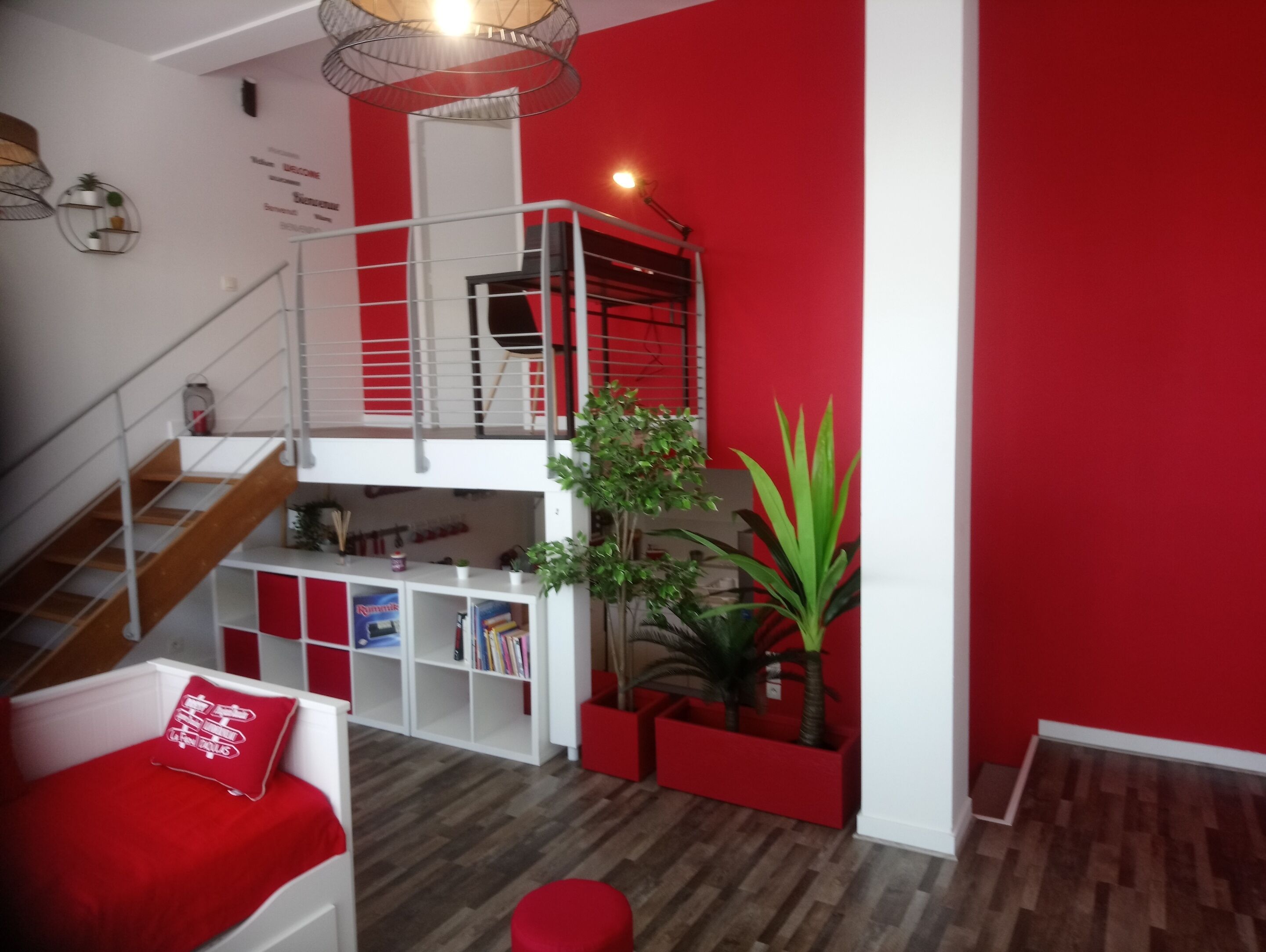 A multi-level living space with a staircase, a red wall, and a wooden floor.