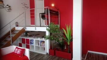 A multi-level living space with a staircase, a red wall, and a wooden floor.