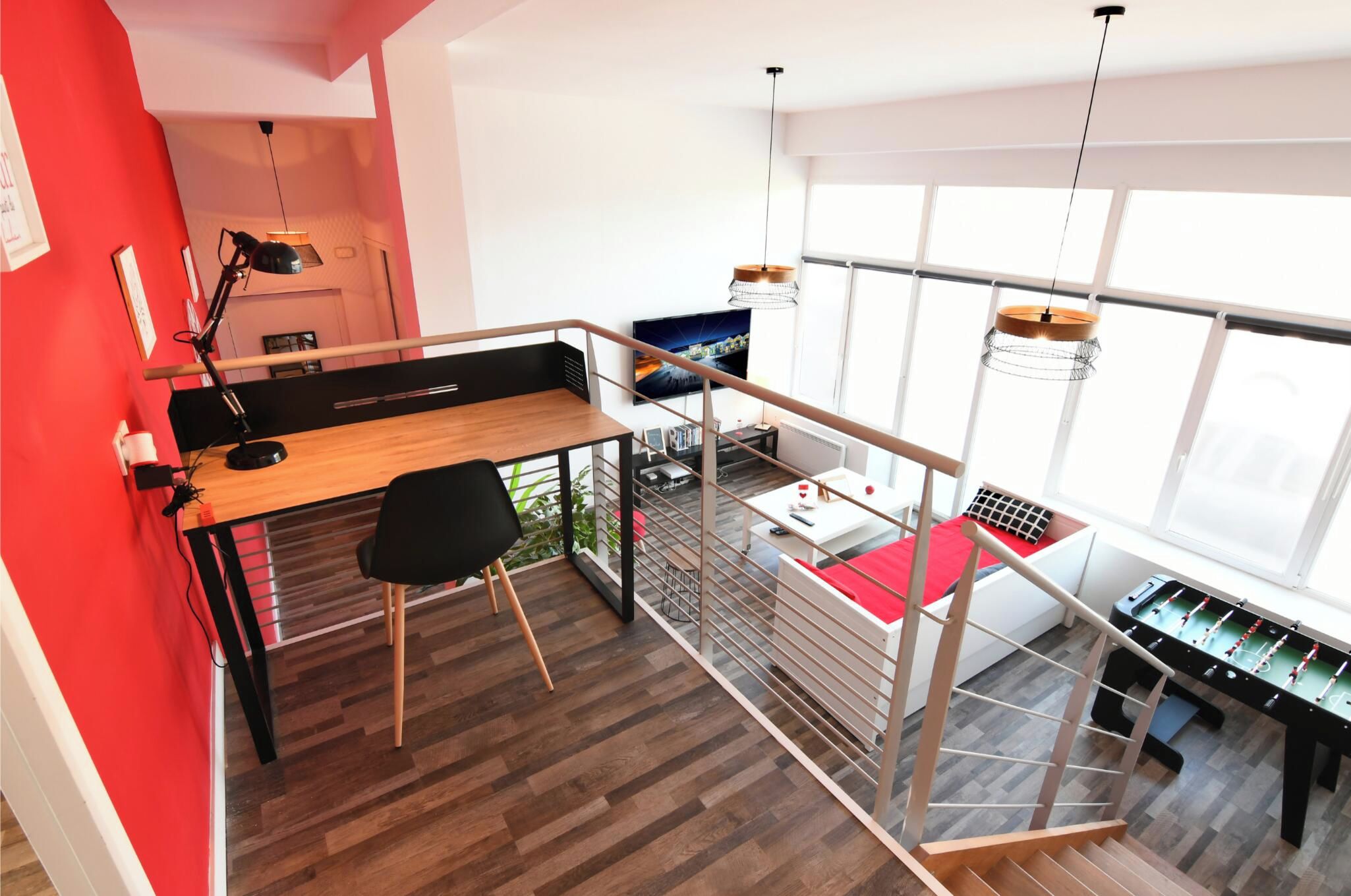 A modern loft apartment with a dining area, a sofa bed, and a foosball table.
