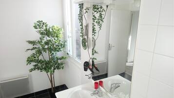 Un baño con un lavamanos blanco, un espejo y una planta en maceta.