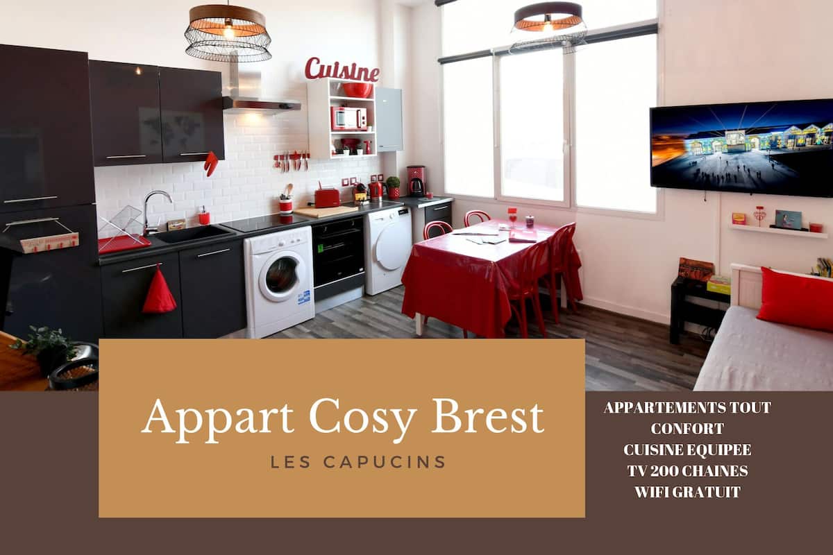A modern apartment with a kitchen, dining area, and a TV. It includes amenities like a washing machine, a TV with 200 channels, and free WiFi.